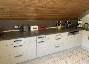 A kitchen with white cabinets, a granite countertop, and a wooden ceiling.