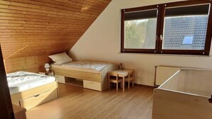 Un dormitorio con techo inclinado, una cama, una mesita y un radiador.