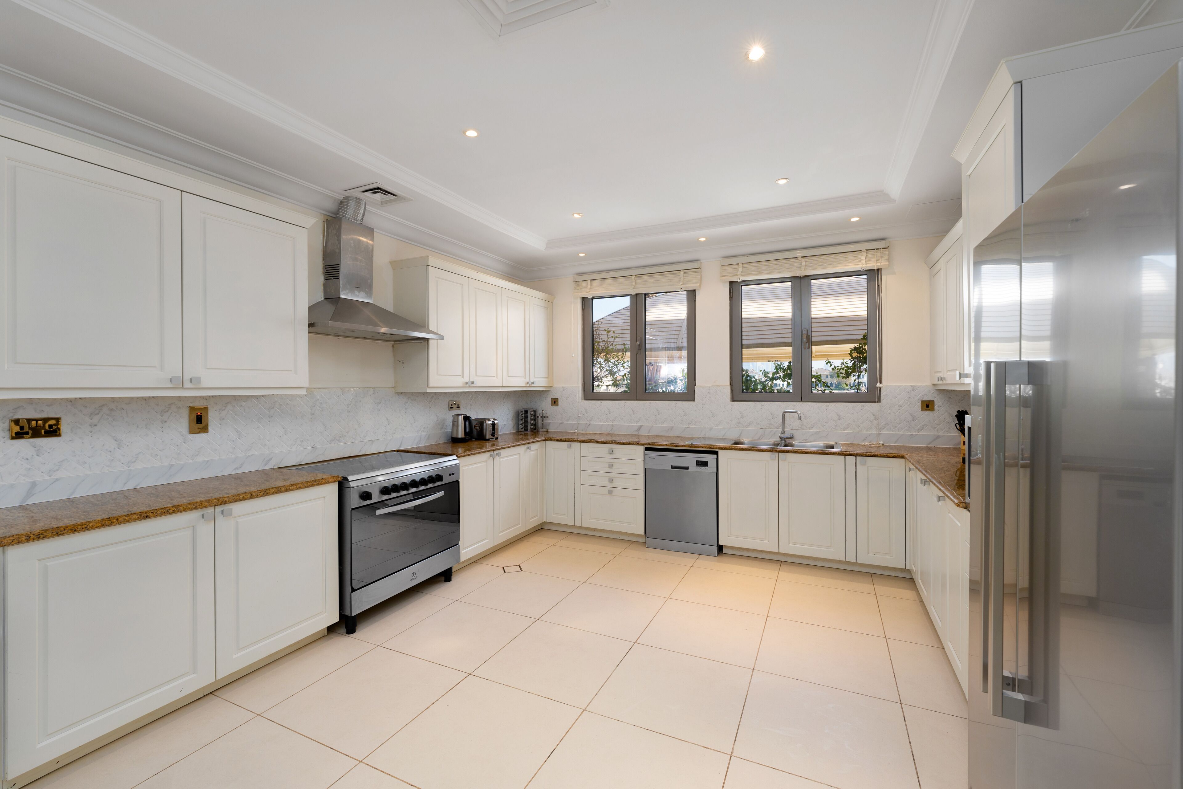 A modern kitchen with white cabinetry, stainless steel appliances, and a tiled floor.