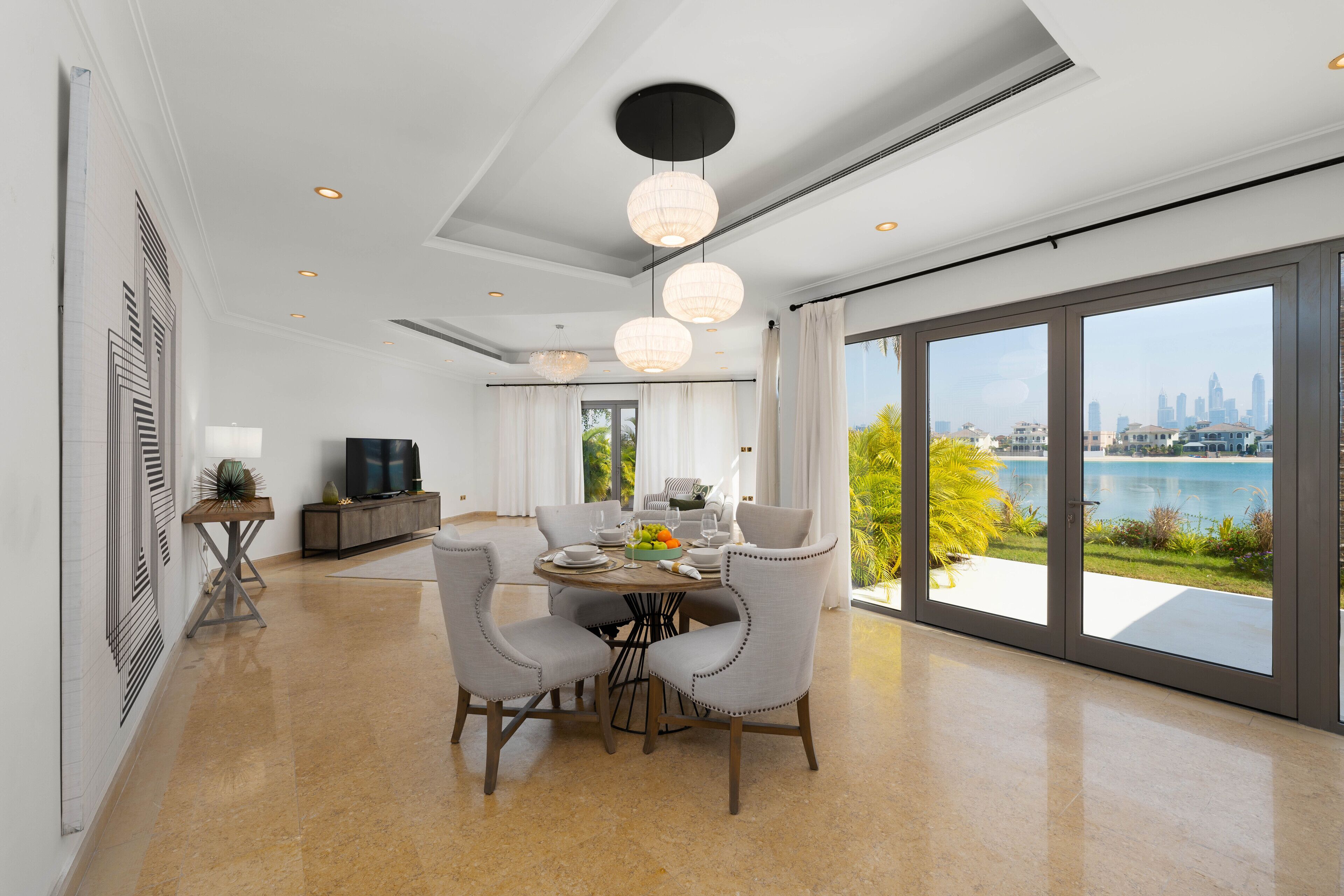 A modern dining area with a table set for four, large windows with a city view, and a ceiling with recessed lighting.