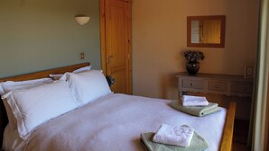 A bedroom with a bed, a wooden door, a dresser, and a mirror. - Cuddfan Lodge on a Beautiful Lake (Newport)