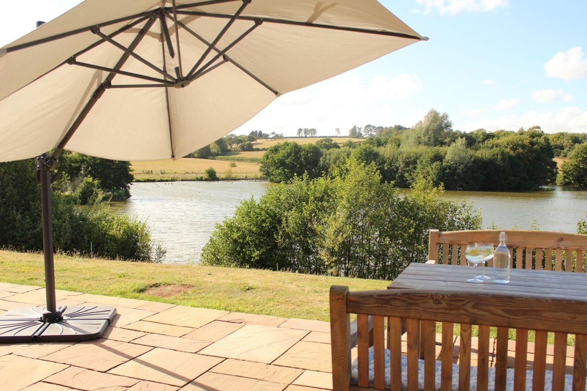 A patio with a table and an umbrella overlooking a river.