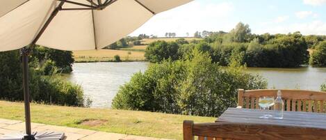 A patio with a table and an umbrella overlooking a river.