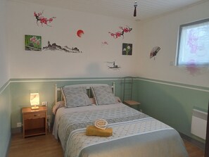 A bedroom with a bed, nightstands, a lamp, and wall art.