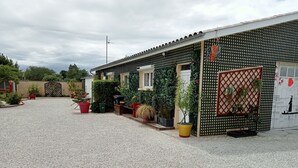 Un edificio con camino de grava, plantas en macetas y valla de celosía.