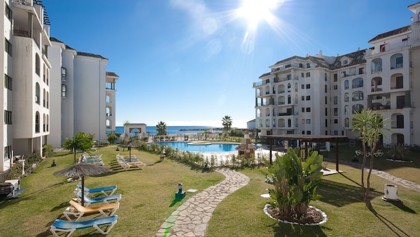 Een resort met een zwembad, ligbedden en uitzicht op de oceaan.