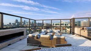 A rooftop terrace with wicker furniture, a grill, and a view of the city skyline. - Walkable Uptown Dallas 3BR with Pool, Pets, Wi-Fi (Dallas)