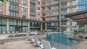 A modern building with a rooftop pool area, multiple balconies, and a covered seating area. - Walkable Uptown Dallas 3BR with Pool, Pets, Wi-Fi (Dallas)
