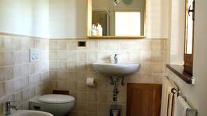 A bathroom with a toilet, bidet, sink, mirror, and towel rack.