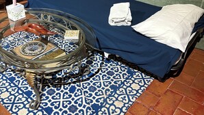 A cozy room with a bed, a green sofa, a patterned rug, and a small table with decorative items.