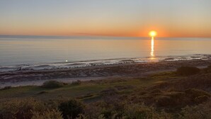 A sunset over a calm sea with a beach in the foreground. - Oasis in Aldinga Beach, an affordable holiday near the beach (Aldinga Beach)