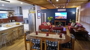 A modern kitchen with a dining area, red sofas, and a TV. - Oasis in Aldinga Beach, an affordable holiday near the beach (Aldinga Beach)
