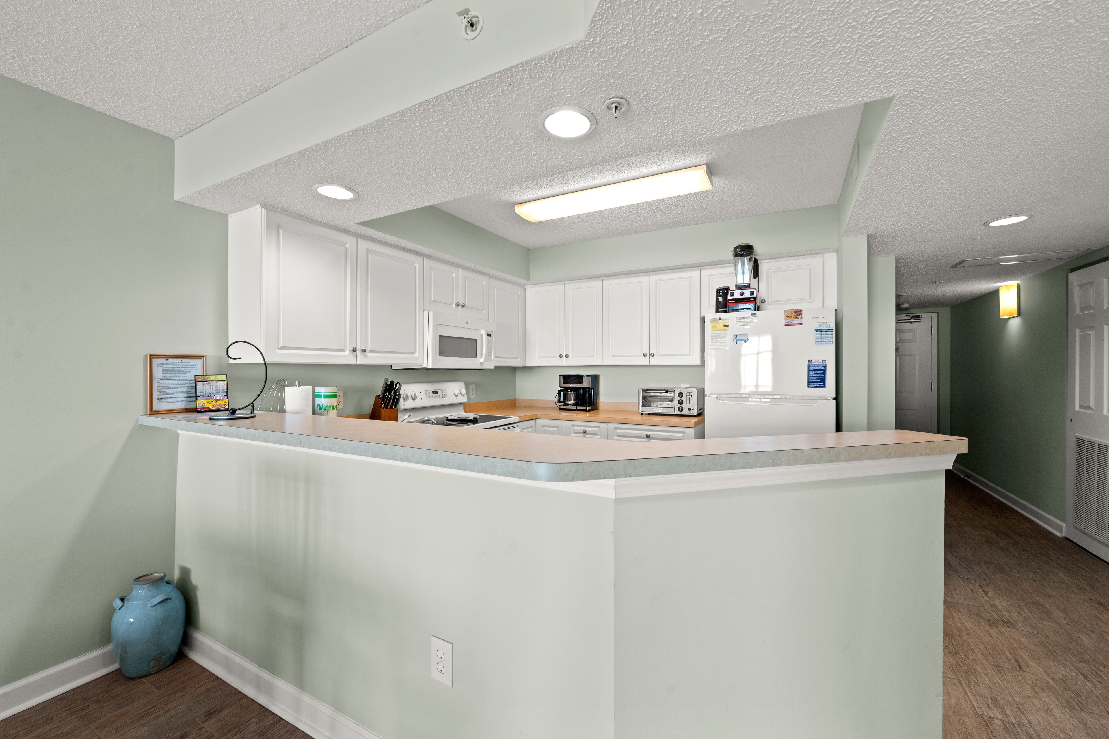 A modern kitchen with white cabinets, a central island, and a microwave.