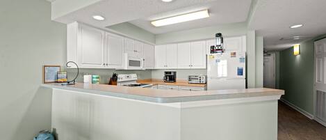 A modern kitchen with white cabinets, a central island, and a microwave.