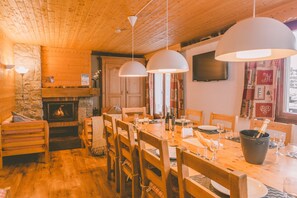Un coin repas chaleureux, avec des meubles en bois, une cheminée et des luminaires suspendus.