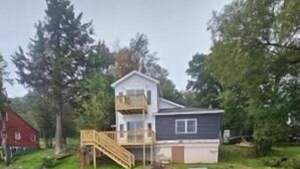 A two-story house with a wooden deck and a small staircase leading to the upper floor.