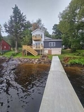 Une maison à deux étages dotée d’une terrasse en bois et d’un petit escalier menant à l’étage supérieur.