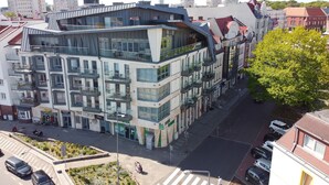 Un edificio de varios pisos con balcones, un restaurante en la planta baja y un banco a la vista.