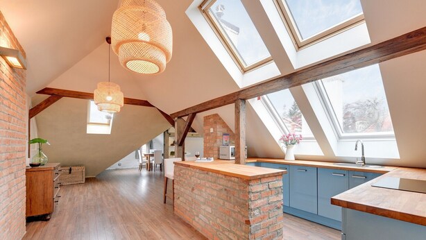 Um loft espaçoso com cozinha, piso de madeira e claraboias.
