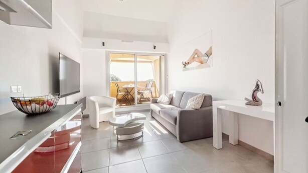 A modern living room with a grey sofa, a white coffee table, and a TV mounted on the wall. - Loft style apartment with Solarium on the last Floor (Cap d'Agde)