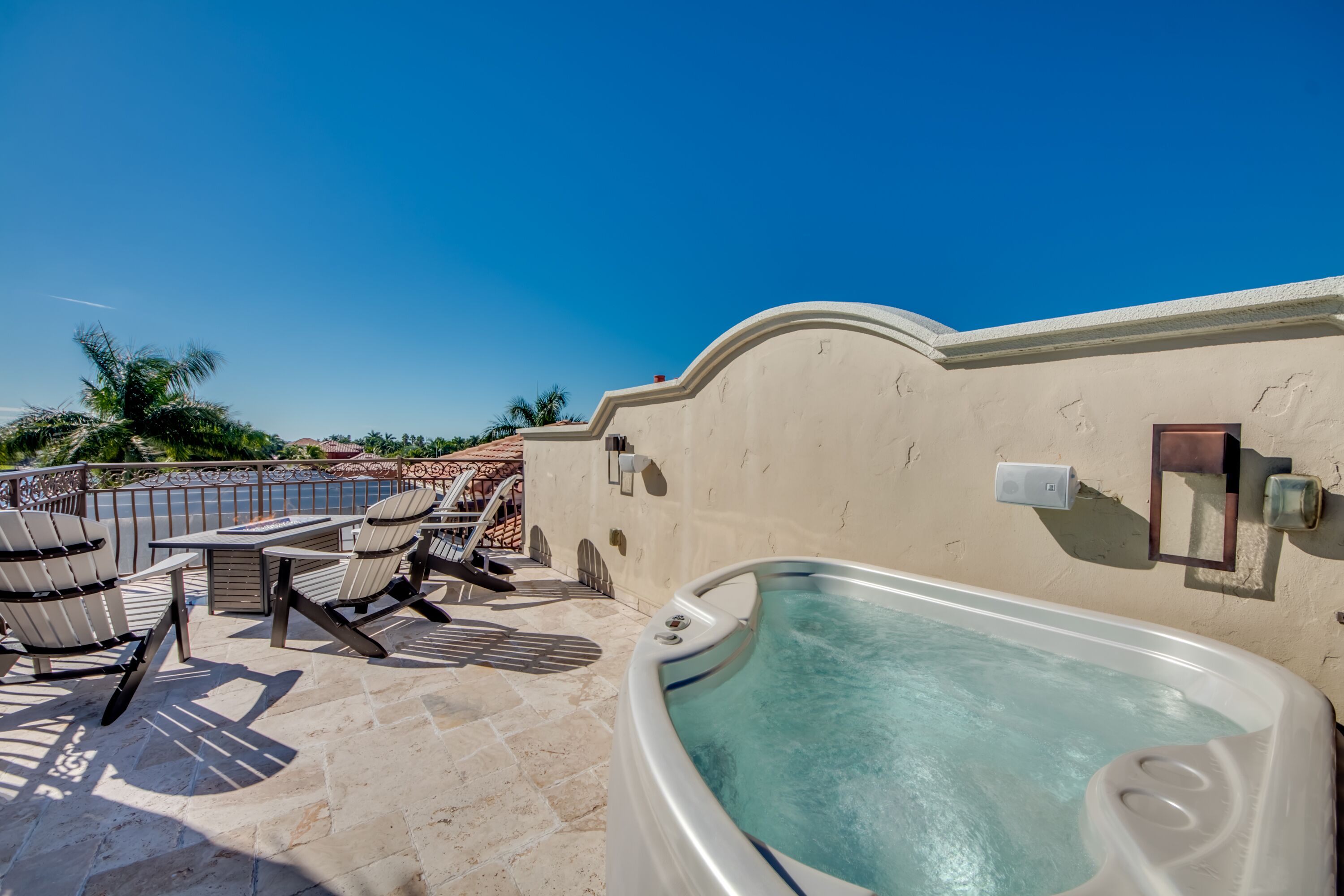 Un área de piscina en la azotea con jacuzzi, sillones de descanso y una mesa.