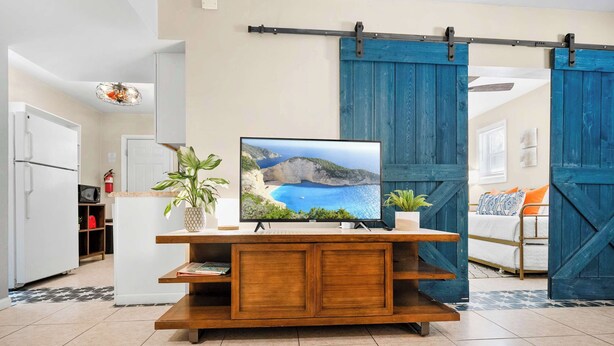 A modern kitchen with a wooden console table, a flat-screen TV, and a sliding barn door.
