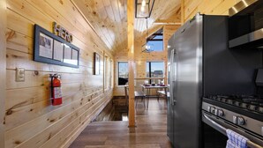 A wooden interior with a black refrigerator, stove, and a fire extinguisher on the wall. - Mountain and City light views! Close to Strip, Private Indoor Pool + Free Tix (Pigeon Forge)