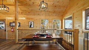A wooden interior with a dining table set for four, a fire extinguisher, and framed pictures on the walls. - Mountain and City light views! Close to Strip, Private Indoor Pool + Free Tix (Pigeon Forge)