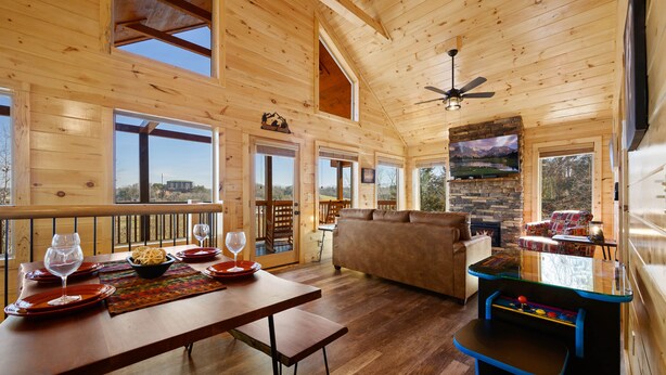 A spacious wooden cabin with a dining area, a living room with a sofa and fireplace, and a game table. - Mountain and City light views! Close to Strip, Private Indoor Pool + Free Tix (Pigeon Forge)