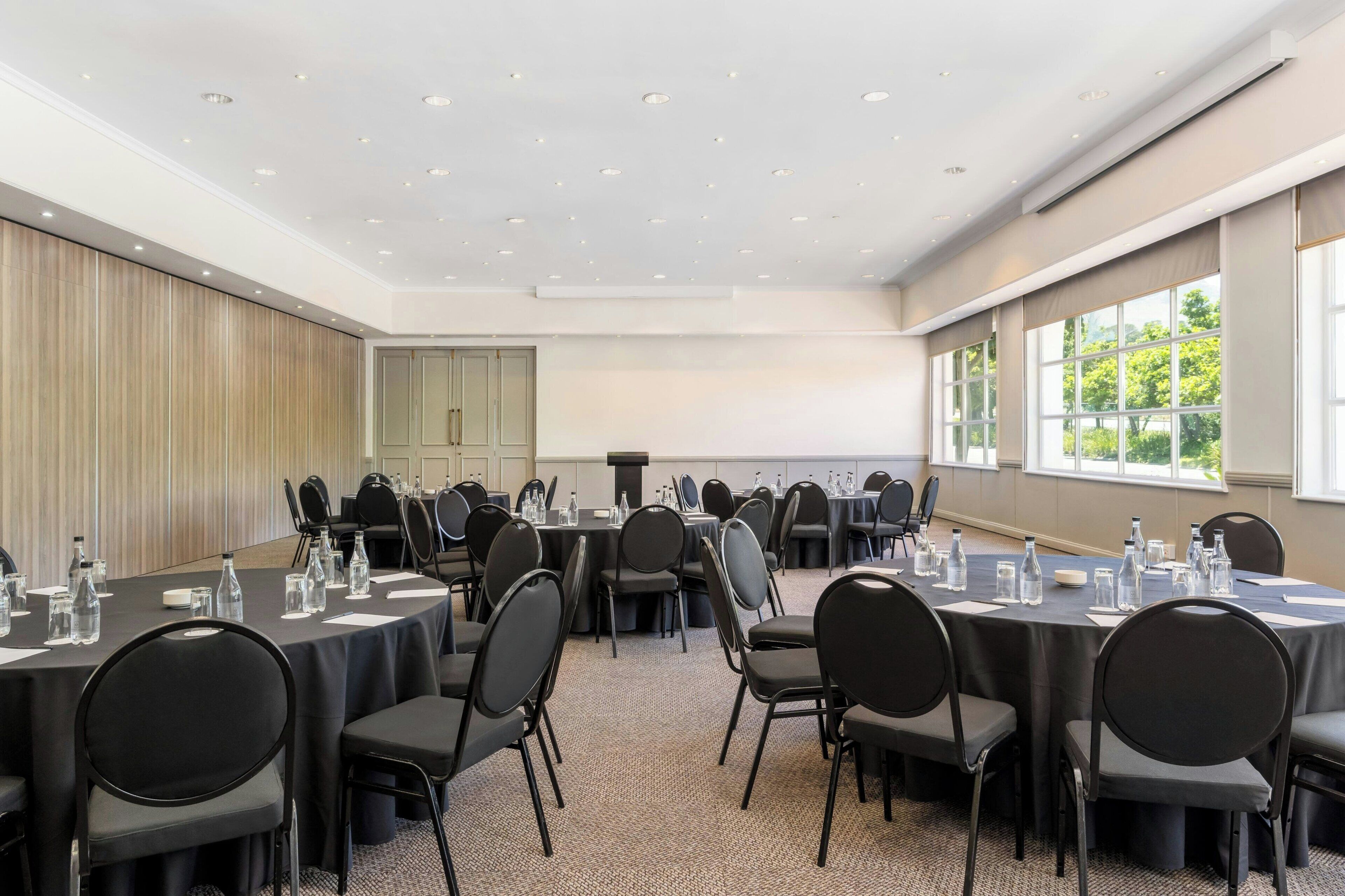 A conference room with round tables, black chairs, and water bottles.