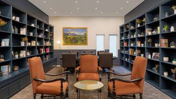 Una biblioteca con estanterías azul oscuro, una mesa redonda y cuatro sillones de cuero.