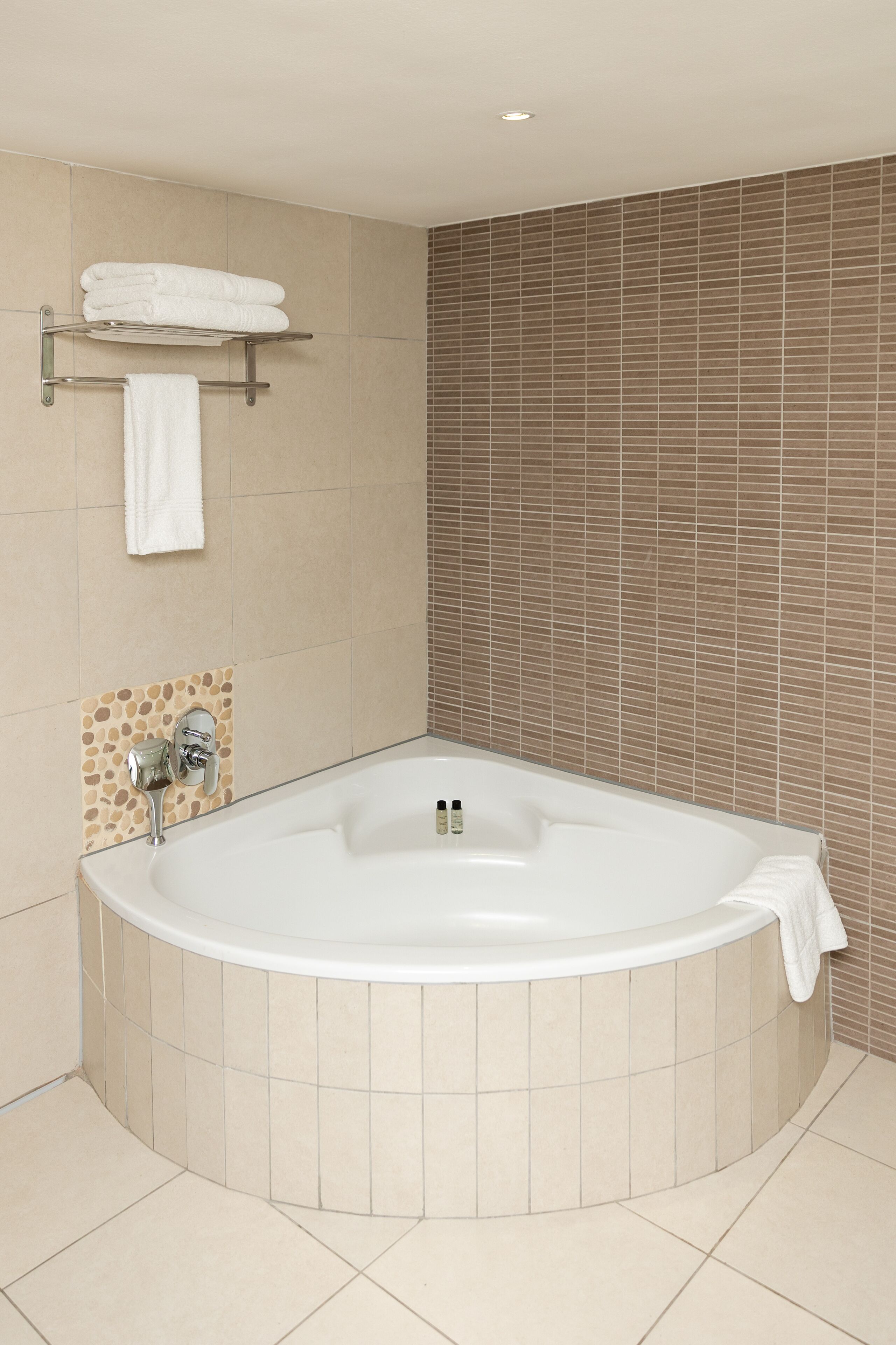 Een moderne badkamer met een vrijstaand bad, een handdoekhouder en een betegelde wand.