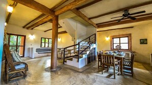 A spacious interior with a wooden staircase, a dining area with chairs and a table, and a large window providing natural light. - Casa Noa master suite 3 steps from the sea (Tulum)