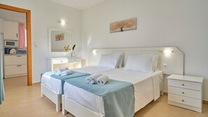 Habitación de hotel con dos camas, una mesita de noche, un espejo y un cuadro en la pared.