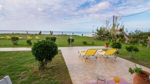 Un patio con una mesa lista para bebidas, sillas y vistas al mar.