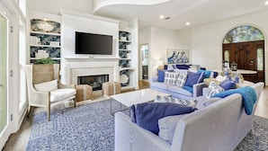 A spacious living room with a fireplace, a television, and a staircase. - Gorgeous 7 Bed 6 & 1-2 Bath Home with Private Heated Pool! (Hilton Head Island)