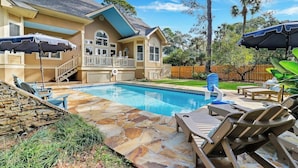 A backyard with a swimming pool, stone patio, and lounge chairs. - Gorgeous 7 Bed 6 & 1-2 Bath Home with Private Heated Pool! (Hilton Head Island)