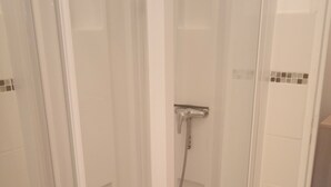 A glass-enclosed shower stall with a handheld showerhead and a tiled floor. - Lovely studio 10 les capucines, Bagnoles de l'Orne town center (Bagnoles de l'Orne Normandie)