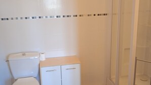 A bathroom with a toilet, a small cabinet, and a shower area. - Lovely studio 10 les capucines, Bagnoles de l'Orne town center (Bagnoles de l'Orne Normandie)
