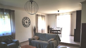 A living room with a sofa, a coffee table, and a dining area with a table and chairs. - At the gateway to the Luberon Regional Nature Park Classified tourist accommodation ★★★ (Cheval-Blanc)