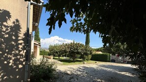 A gravel driveway leading to a building with a stone wall and a tree in the foreground. - At the gateway to the Luberon Regional Nature Park Classified tourist accommodation ★★★ (Cheval-Blanc)