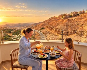 A dining table with breakfast items and a scenic view of a mountainous landscape. - Petra Canyon Hotel (Wadi Musa)