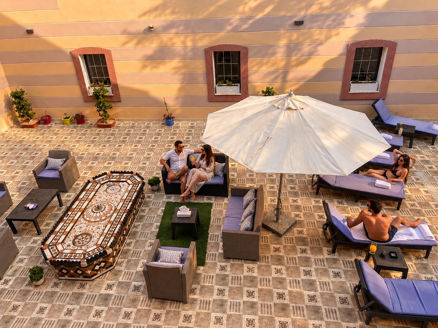 A rooftop terrace with lounge chairs, a patterned floor, and potted plants.
