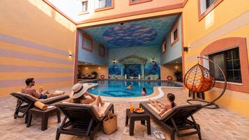 A pool area with lounge chairs, a hanging chair, and a decorative ceiling.