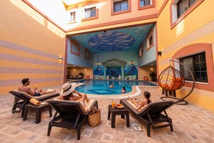 Un área de piscina con sillones de descanso, una hamaca colgante y un techo decorativo.