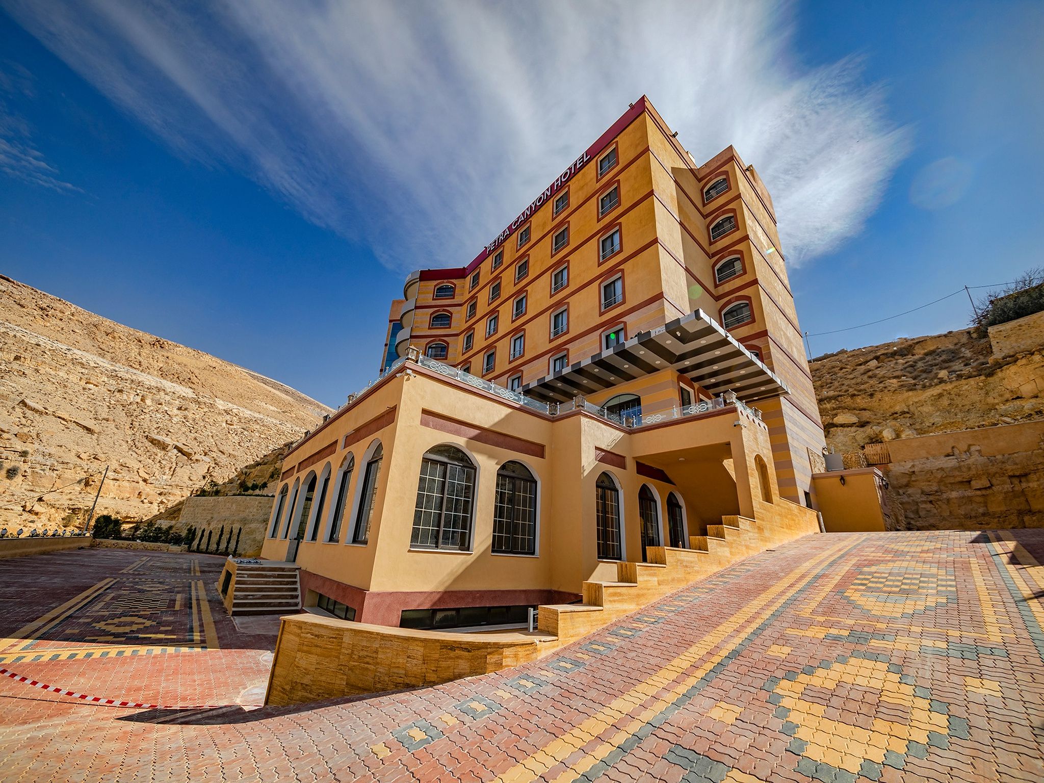 A hotel with multiple floors, a prominent entrance with steps, and a patterned pavement.