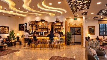 Zona de bar con asientos, una recepción y una cocina al fondo.