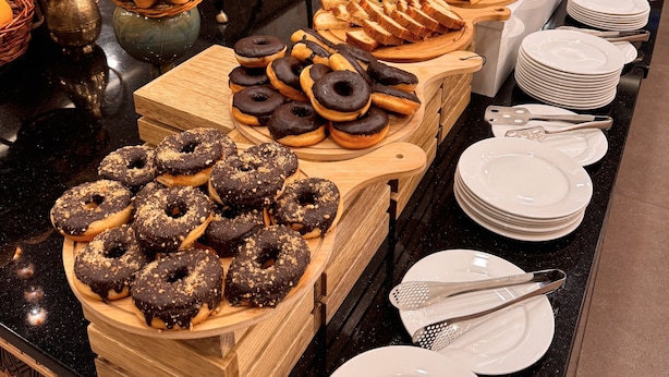 A buffet with various food items, including donuts and pastries, arranged on a counter. - Petra Canyon Hotel (Wadi Musa)