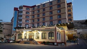 A multi-story hotel with a prominent entrance, balconies, and a clear sky. - Petra Canyon Hotel (Wadi Musa)