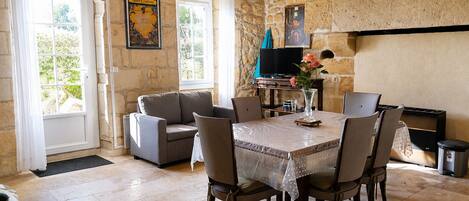 A dining area with a table set for four, a sofa, a television, and a fireplace.